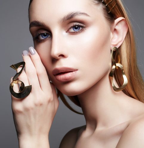 Gold jewelry on beautiful girl with blue eyes. young blonde woman with make-up and jewels accessories. Beauty Fashion Portrait